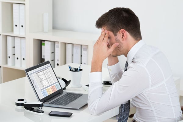 stockfresh_6279683_businessman-suffering-from-headache-at-desk_sizeM