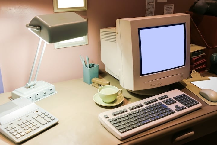 Man jumping out of an old computer desktop into a newer laptop computer